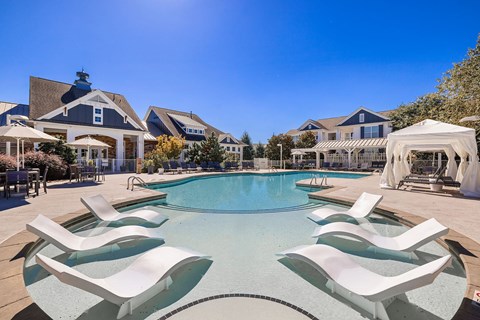 A pool surrounded by white lounge chairs.