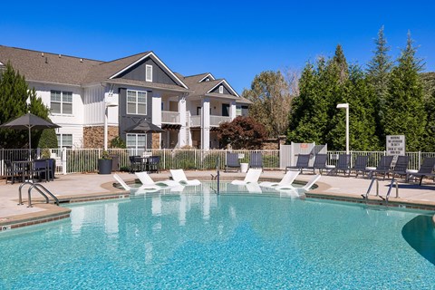 A large swimming pool in front of a multi-story apartment building.
