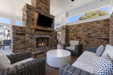 A living room with a stone fireplace and a television above it.