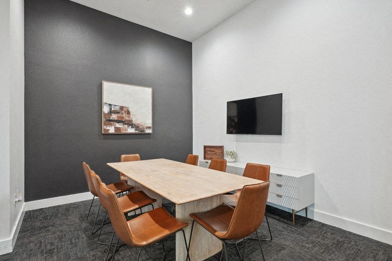 a conference room with a table and chairs and a television