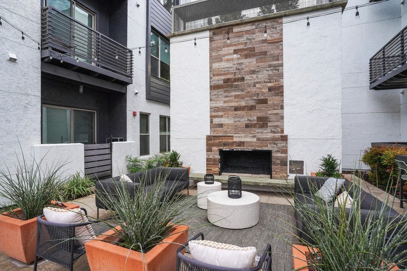 a courtyard with a fireplace and chairs and plants