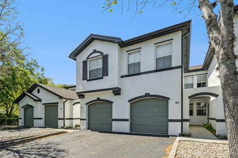 A white house with black trim and a grey garage door.