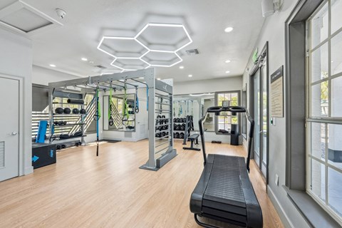 A gym with a variety of equipment including a treadmill, weights, and a bench.