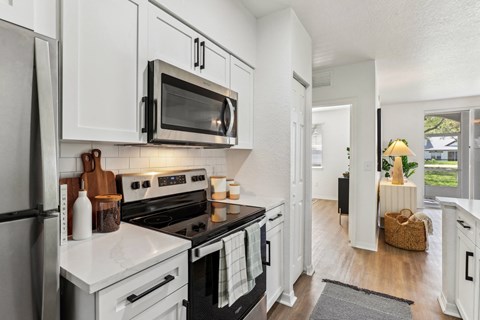 a kitchen with white cabinets and a black stove and a microwave