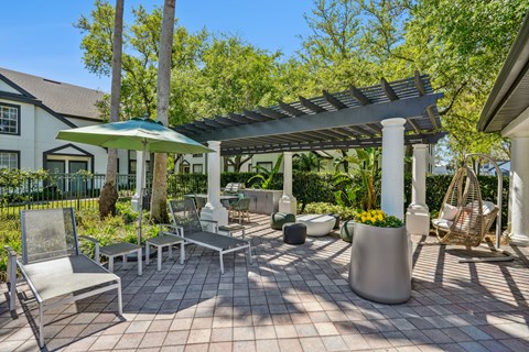 A patio with a white pergola and a green umbrella.