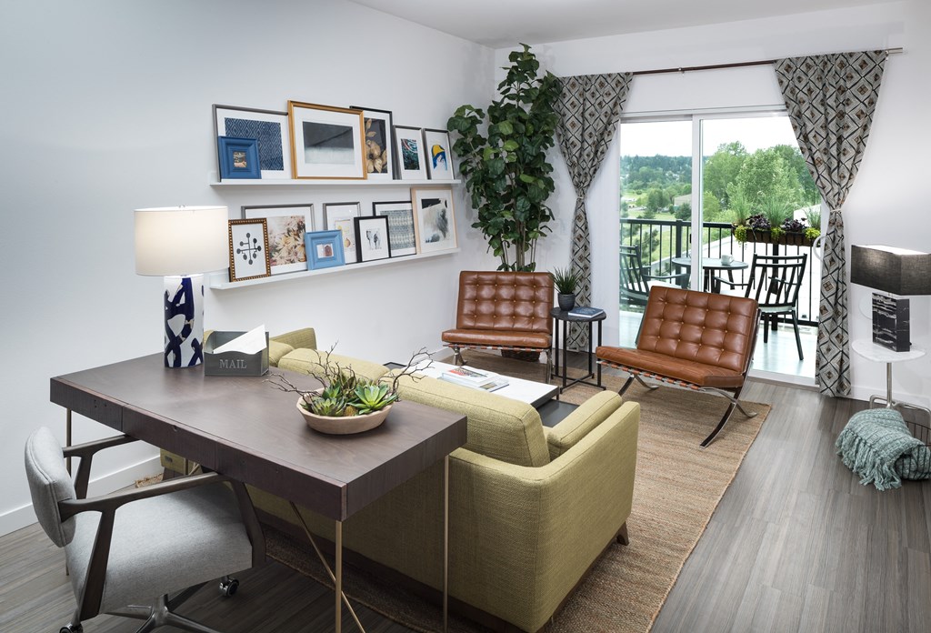 a living room with a desk and chairs and a window