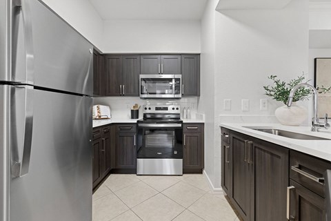 A modern kitchen with dark wood cabinets and stainless steel appliances.