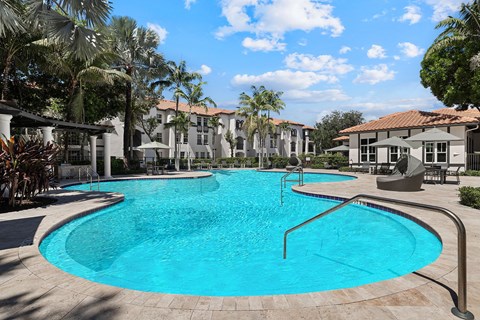 A large swimming pool in a resort with a blue tiled edge.