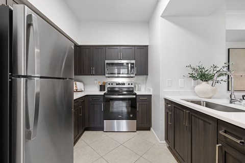A modern kitchen with a stainless steel refrigerator and dark brown cabinets.