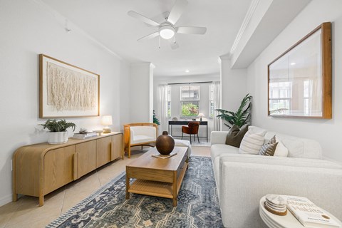 A living room with a white couch, a wooden coffee table, and a large painting on the wall.