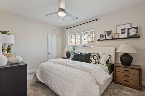 a bedroom with white walls and a white bed with a white comforter