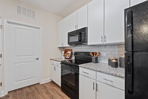 a kitchen with white cabinets and black appliances