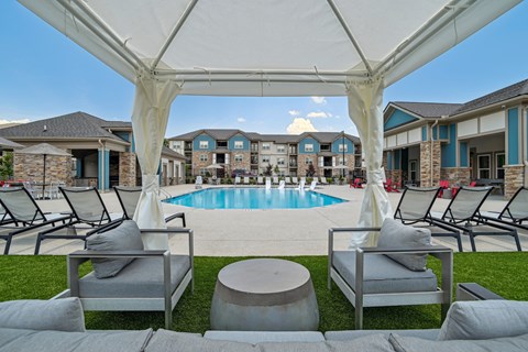 an outdoor lounge area with chairs and a swimming pool