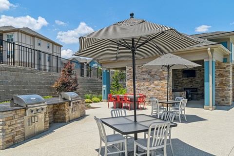 our patio with tables and chairs and a grill and umbrellas