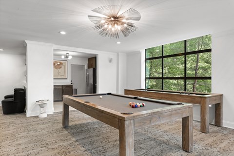 A pool table in a room with a large window.