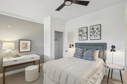 A bedroom with a bed, nightstand, and a ceiling fan.