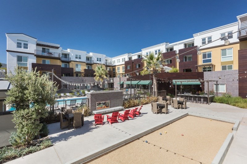 an outdoor patio with red chairs and a pool at an apartment complex