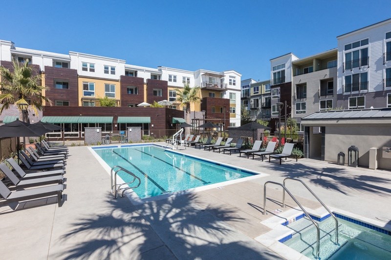 a swimming pool with lounge chairs in front of an apartment building