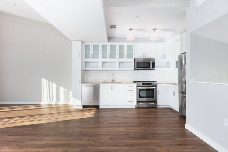 an empty kitchen with white cabinets and stainless steel appliances