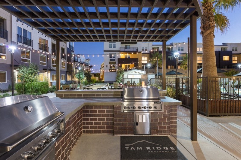 a barbecue grill in the middle of a patio with an apartment building