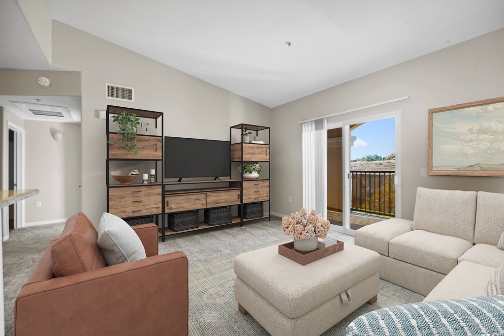A living room with a brown couch, a white ottoman, and a painting on the wall.