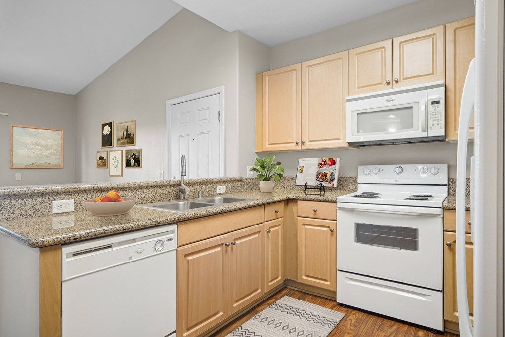 A kitchen with white appliances and wooden cabinets.