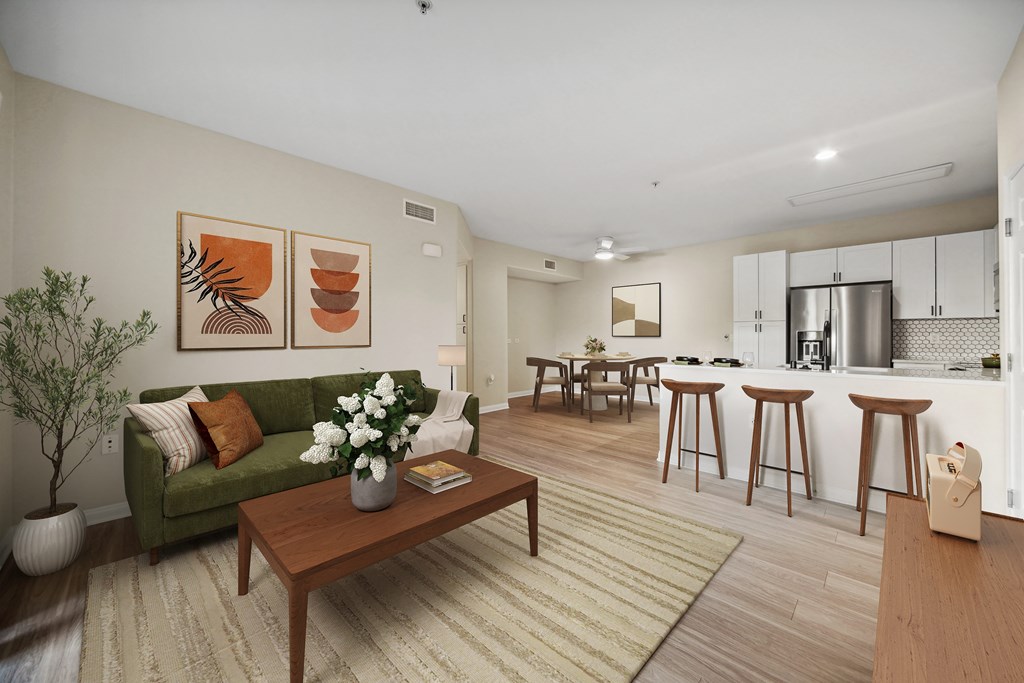 A living room with a green couch, a coffee table, and a dining area in the background.