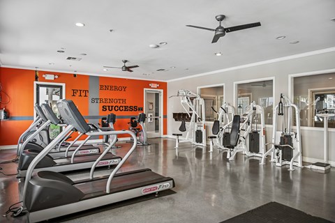 A gym with orange walls and a treadmill in the foreground.