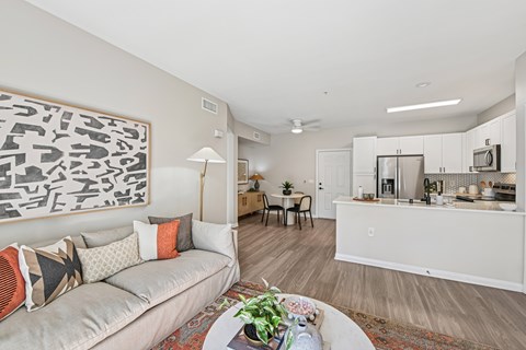 A living room with a grey couch and a large abstract painting on the wall.