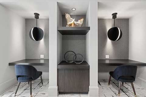 A grey and white room with a desk, chair and shelf.