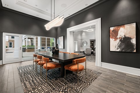 A modern dining room with a black table and orange chairs.