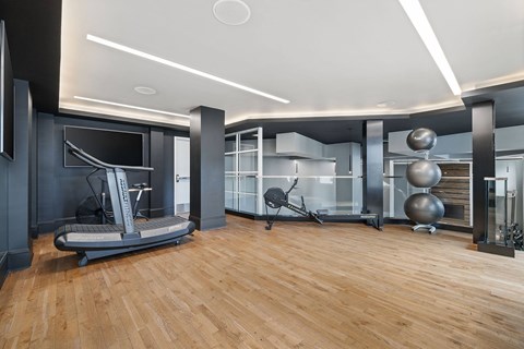 A modern home gym with a wooden floor and various exercise equipment.