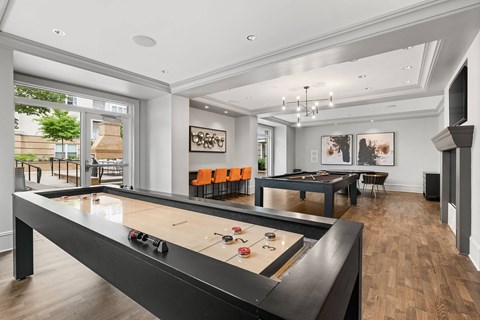 A pool table in a room with a high ceiling and a view of the outdoors.