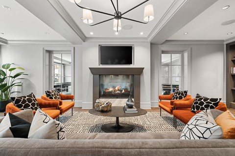 A living room with a grey sofa, orange chairs, a fireplace, and a television.