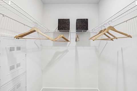 a white room with three wooden chairs and a white wall with two black baskets on