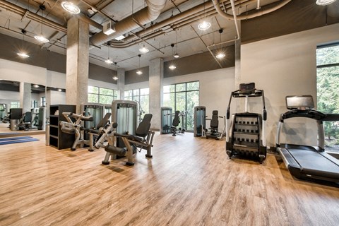 a gym with cardio machines and weights on a wooden floor