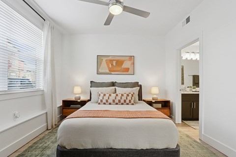 A bedroom with a large bed and a ceiling fan.