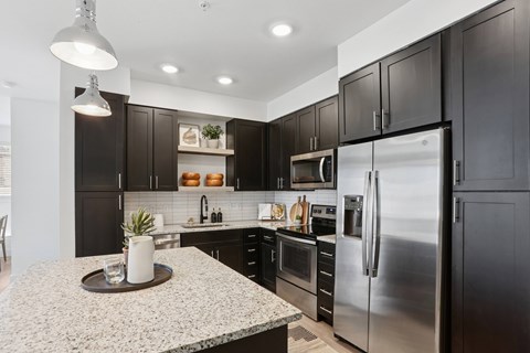 A modern kitchen with dark brown cabinets and stainless steel appliances.