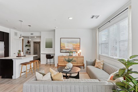 A living room with a grey couch and a painting on the wall.