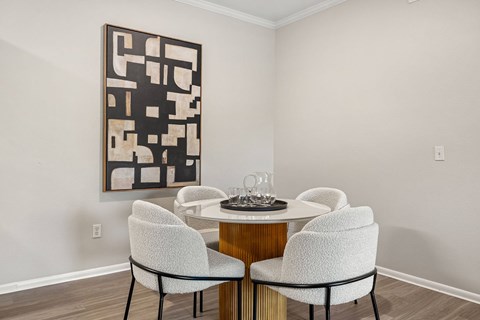 A dining room with a table and chairs and a large abstract painting on the wall.