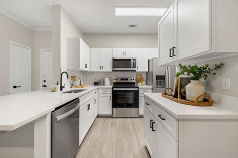 A modern kitchen with white cabinets and stainless steel appliances.