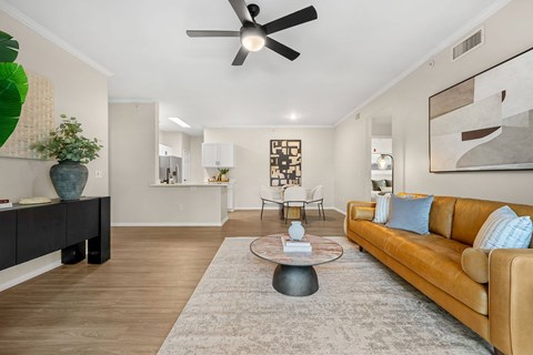 A living room with a brown couch and a ceiling fan.