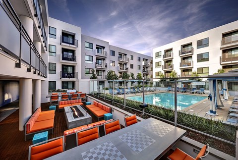 A modern outdoor seating area with orange cushions and a pool in the background.