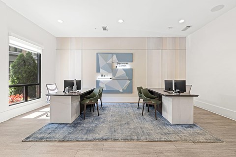 A modern office space with a desk, chairs, and a large window.