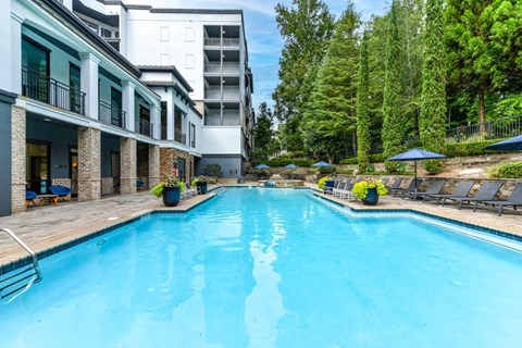 a swimming pool with a building and trees in the background