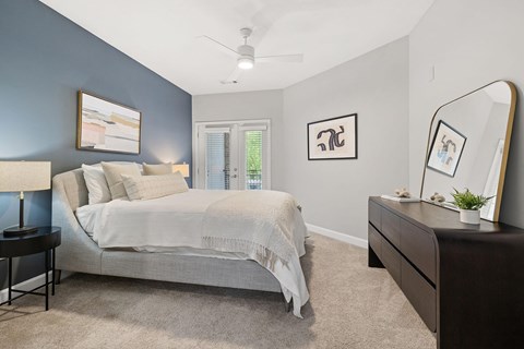 A bedroom with a bed, nightstand, and a ceiling fan.