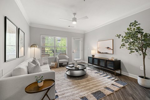 A living room with a grey couch, a coffee table, a side table, a plant, and a painting on the wall.