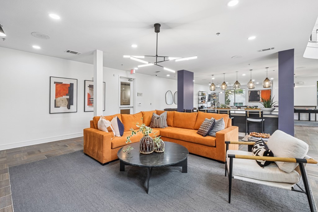 A living room with a grey carpet and a ceiling fan.