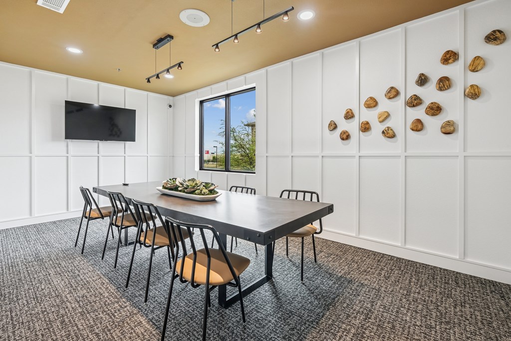 A conference room with a long table and chairs, a television on the wall, and decorative shells on the wall.