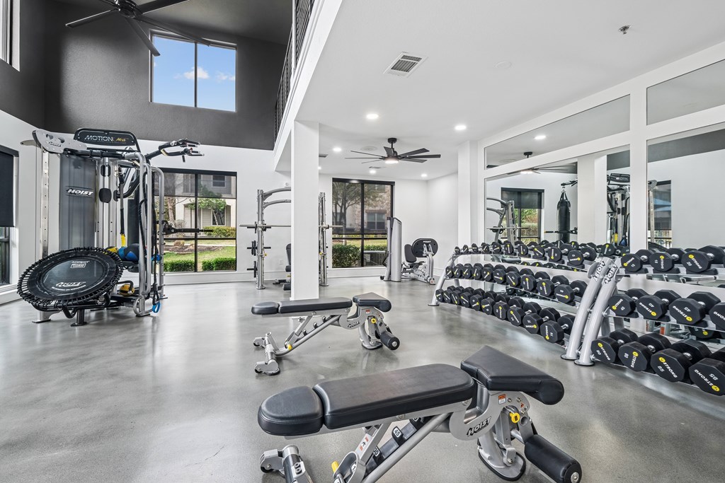 A spacious gym with a variety of equipment including a treadmill, weights, and a bench press.